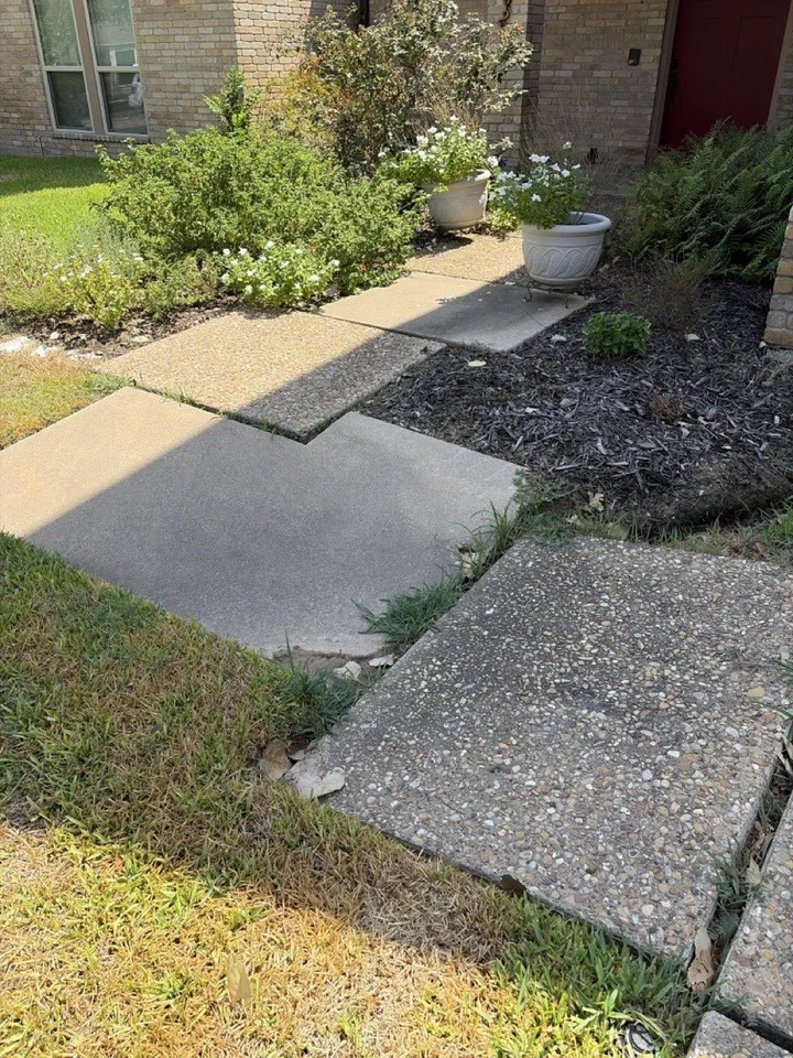 Before the work: heaved and broken walkway slabs beside flower beds