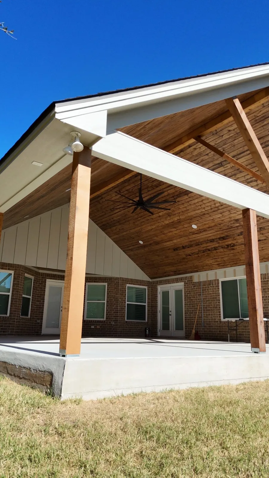 Finished gable patio cover with a stained cedar ceiling, white fascia and a new slab